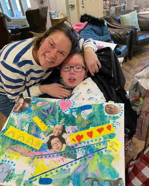 A photo of Evie in her wheelchair displaying her lovely artwork